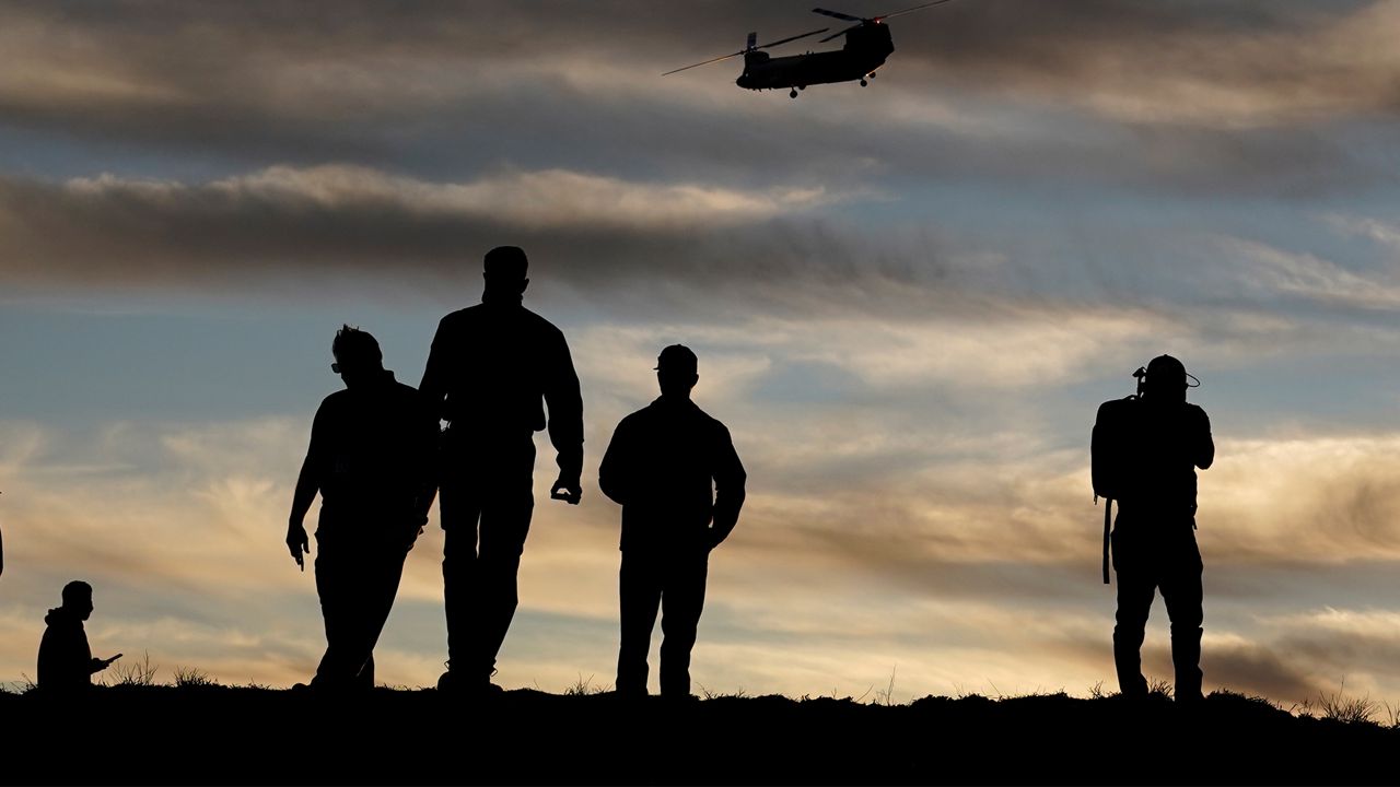 Firefighters watch a Chinook CH-47 helitanker take flight during a demonstration Tuesday, Nov. 17, 2020, in the Santa Monica Mountains west of Los Angeles. (AP Photo/Marcio Jose Sanchez)