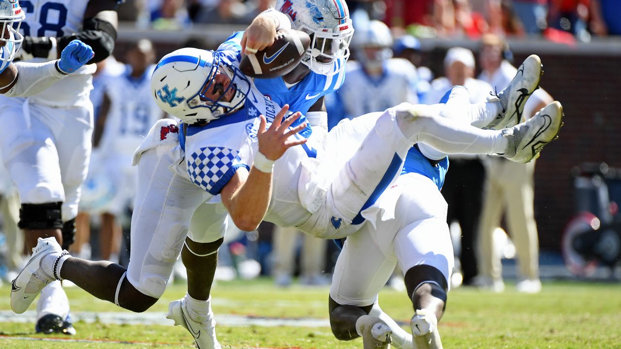 Mississippi safety AJ Finley (21) and linebacker Austin Keys (11) force a fumble from Kentucky quarterback Will Levis (7) during the second half of an NCAA college football game in Oxford, Miss., Saturday, Oct. 1, 2022. Mississippi won 22-19. (AP Photo/Thomas Graning)