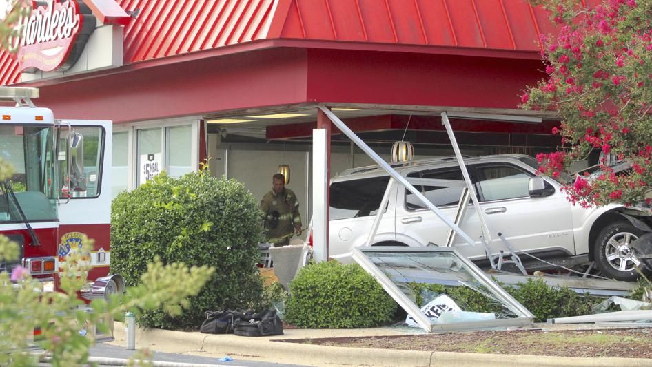 A Wilson, N.C., Fire/Rescue Services firefighter stands behind a sport-utility vehicle that crashed into a Hardee’s restaurant on Sunday, Aug. 14, 2022, in Wilson. (Drew C. Wilson/The Wilson Times via AP)
