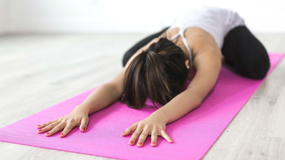 A woman performs child's pose on a yoga mat. (Pixabay)