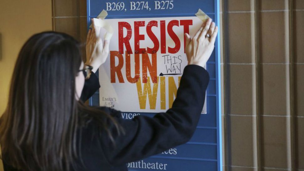 In this Saturday, Dec. 9, 2017 photo, Lianna Stroster posts a sign directing to a women's candidate training workshop at El Centro College in Dallas. EMILY'S List, is an organization dedicated to electing candidates at all levels of government who support abortion rights, is conducting a national recruitment effort looking to train candidates and potential candidates in over 20 states. (AP Phot0/LM Otero)