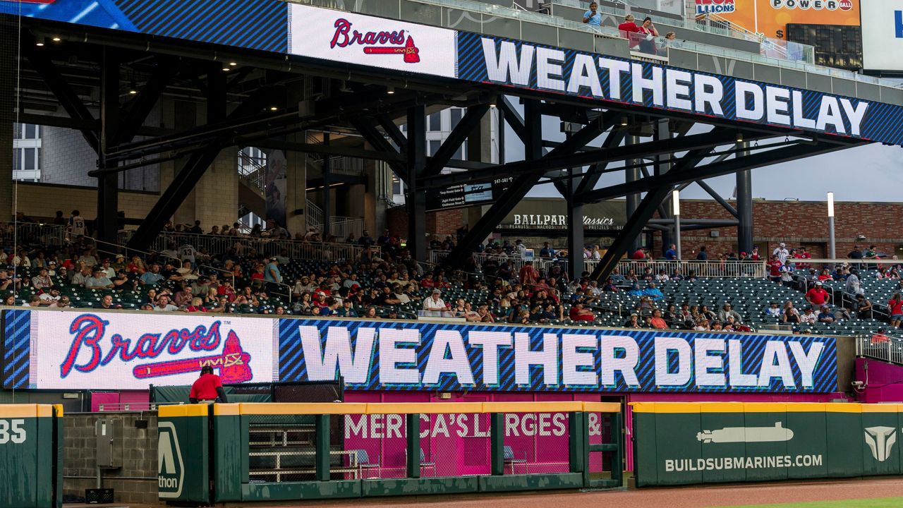 Scoreboards above the visiting team's bullpen announce the weather delay during a baseball game between the Cincinnati Reds and the Atlanta Braves, Tuesday, July 23, 2024, in Atlanta. (AP Photo/Jason Allen)