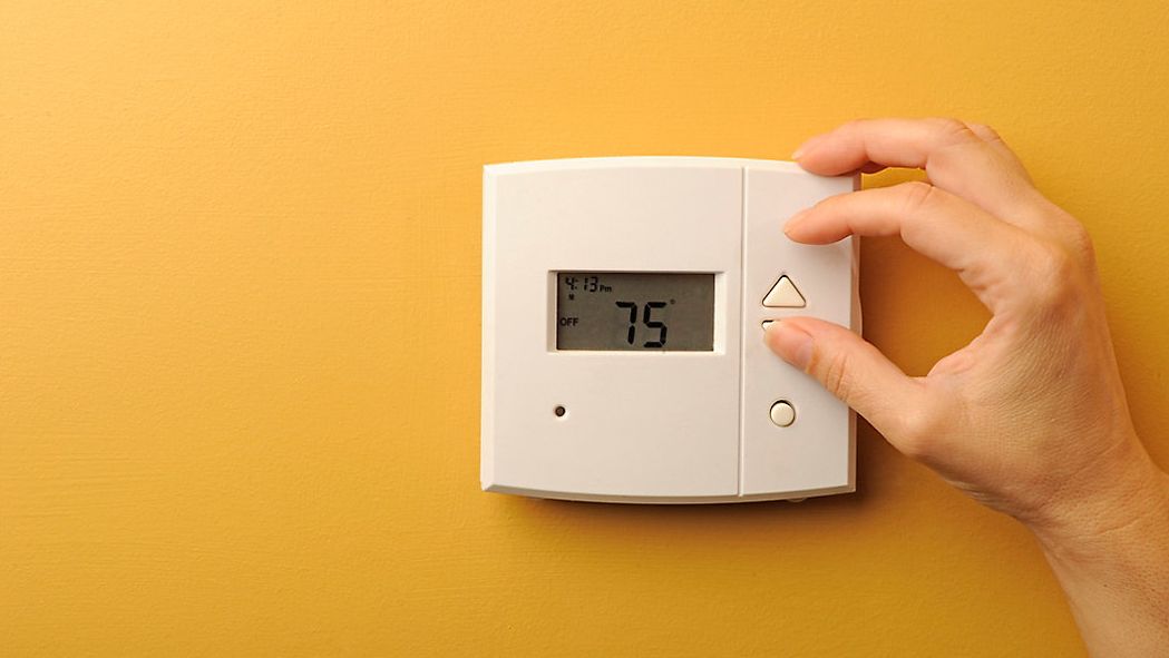 A person adjusts a thermostat in this file image. (Spectrum News 1/FILE)