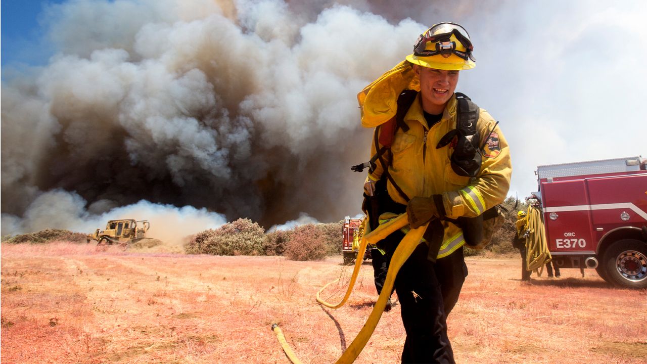 A firefighter battles a brush fire at the Apple Fire in Cherry Valley, Calif., Saturday, Aug. 1, 2020. A wildfire northwest of Palm Springs flared up Saturday afternoon, prompting authorities to issue new evacuation orders as crews fought the blaze in triple-degree heat. The blaze began as two separate fires Friday evening in Cherry Valley, an unincorporated area near the city of Beaumont in Riverside County. (AP Photo/Ringo H.W. Chiu)