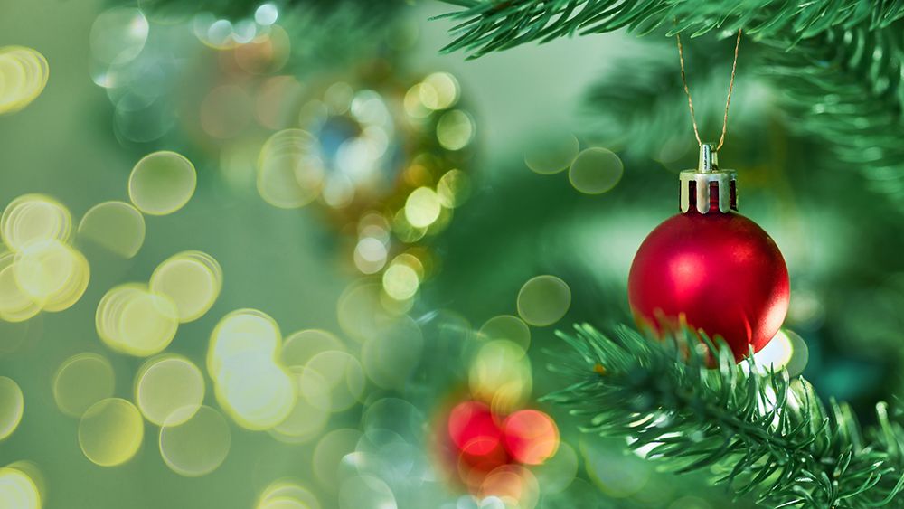 Christmas ornaments on green branches with blurred background, bokeh and garlands lights. (Getty Images)