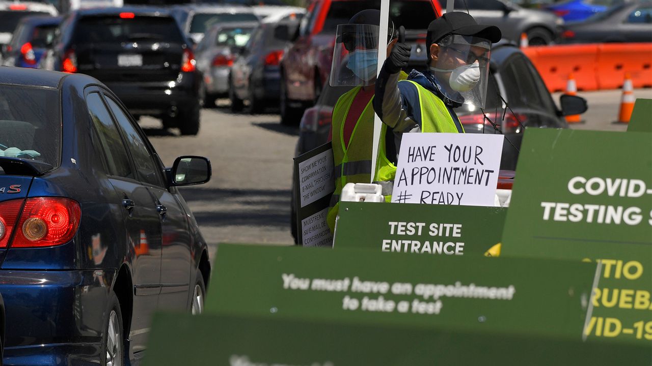 Workers direct cars as they wait in line for coronavirus testing at Dodger Stadium Tuesday, July 14, 2020, in Los Angeles. (AP Photo/Mark J. Terrill)