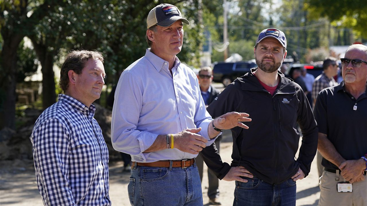 Republican vice presidential nominee Sen. JD Vance, R-Ohio, listens to Virginia Gov. Glenn Youngkin as he visits areas impacted by Hurricane Helene in Damascus, Va., Thursday Oct. 3, 2024. At left is state Sen. Todd Pillion. (AP Photo/Steve Helber)