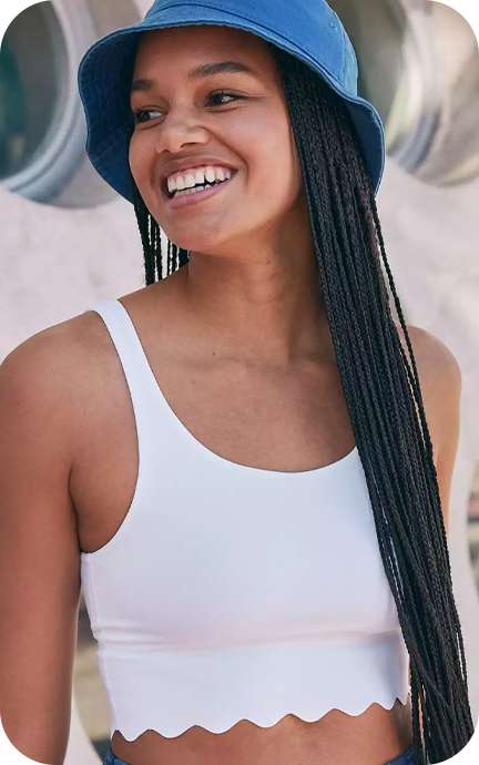 girl smiling wearing white bra top and blue bucket hat