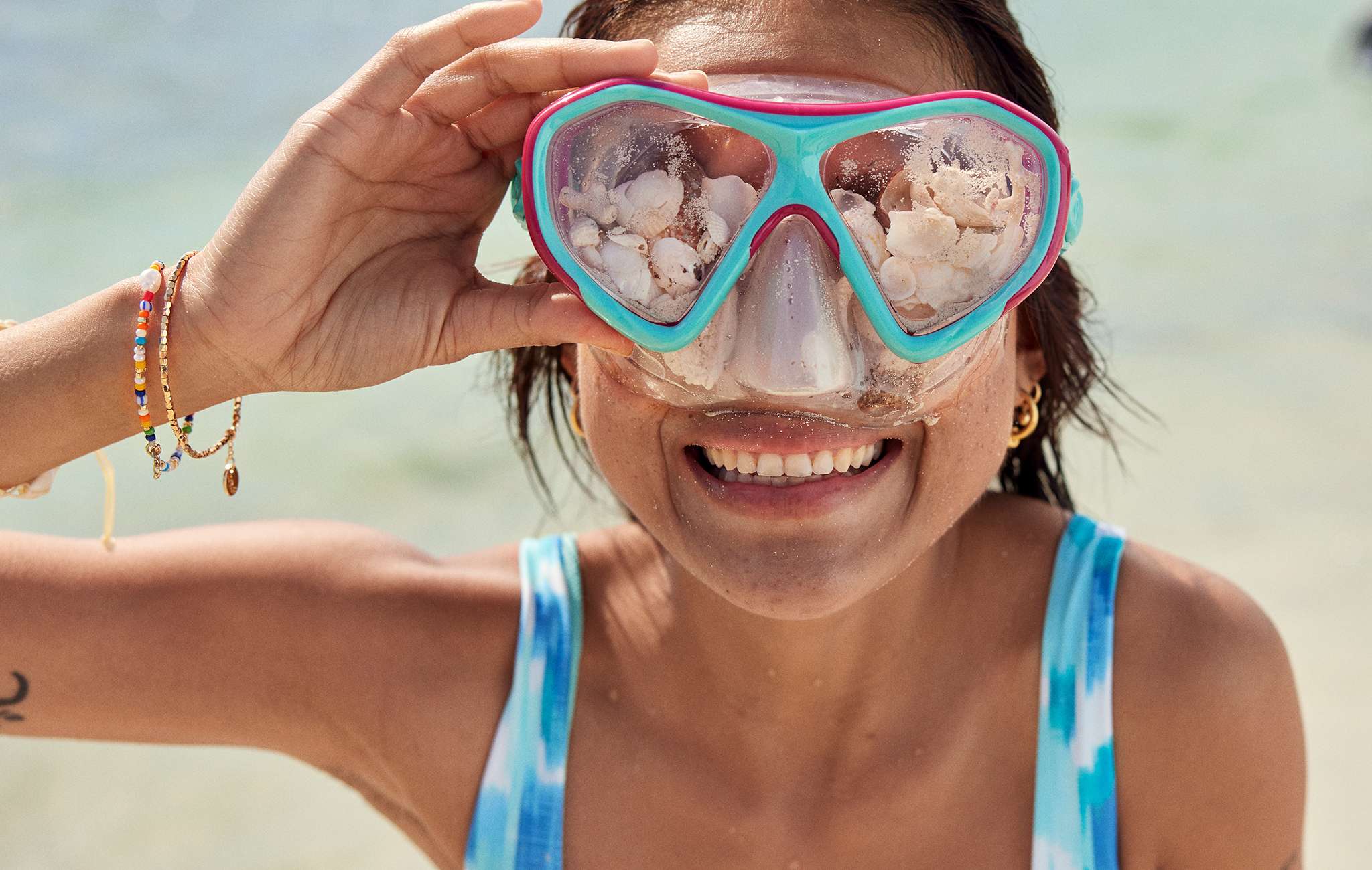 woman on beach wearing goggles with seashells in them 