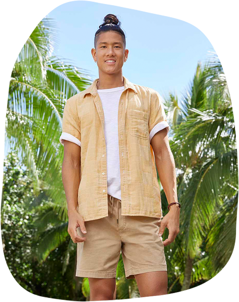 model in white tee with yellow button up resort shirt layered and khaki shorts