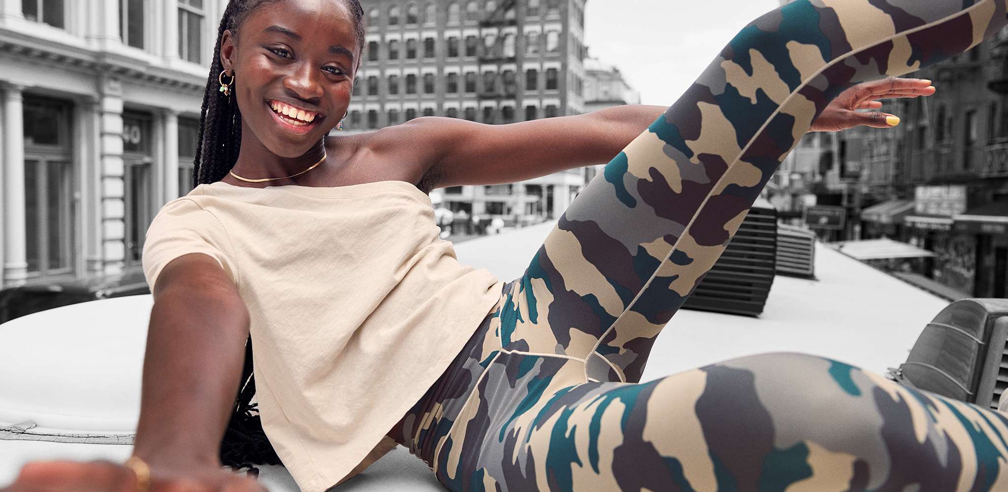 woman sitting on roof in the city wearing camouflage print offline leggings