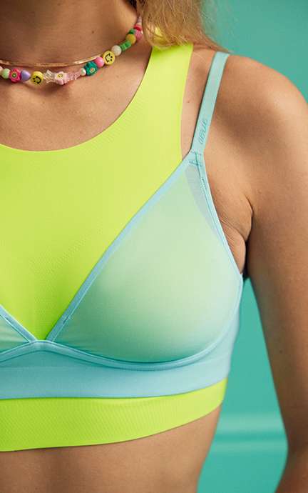 model in a lime green SMOOTHEZ lounge bra with a turquoise mesh bra layering overtop