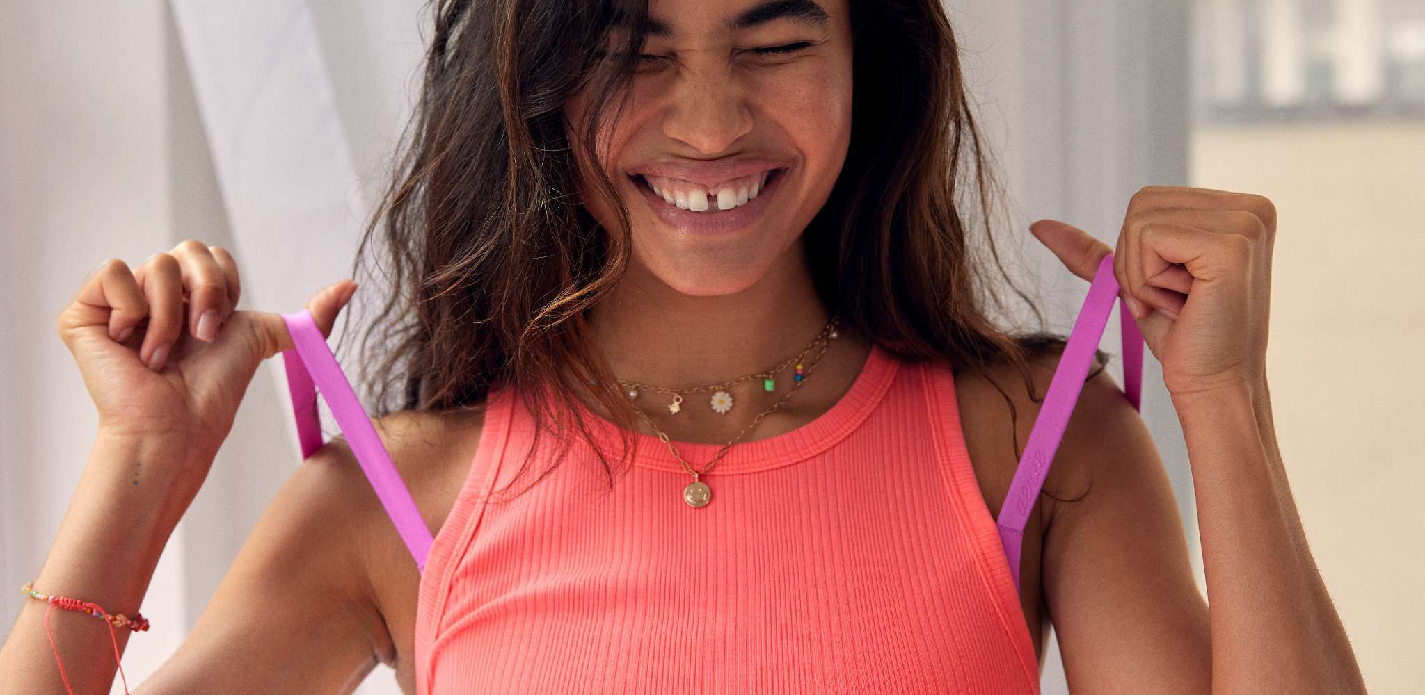 woman smiling wearing tank top and pulling bra straps 