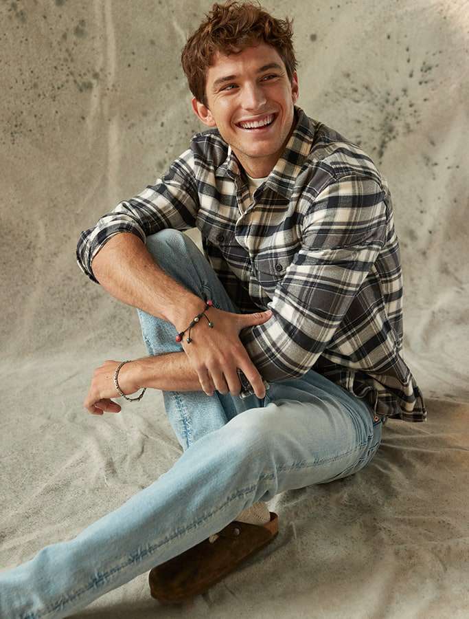 model in plaid button up and denim jeans