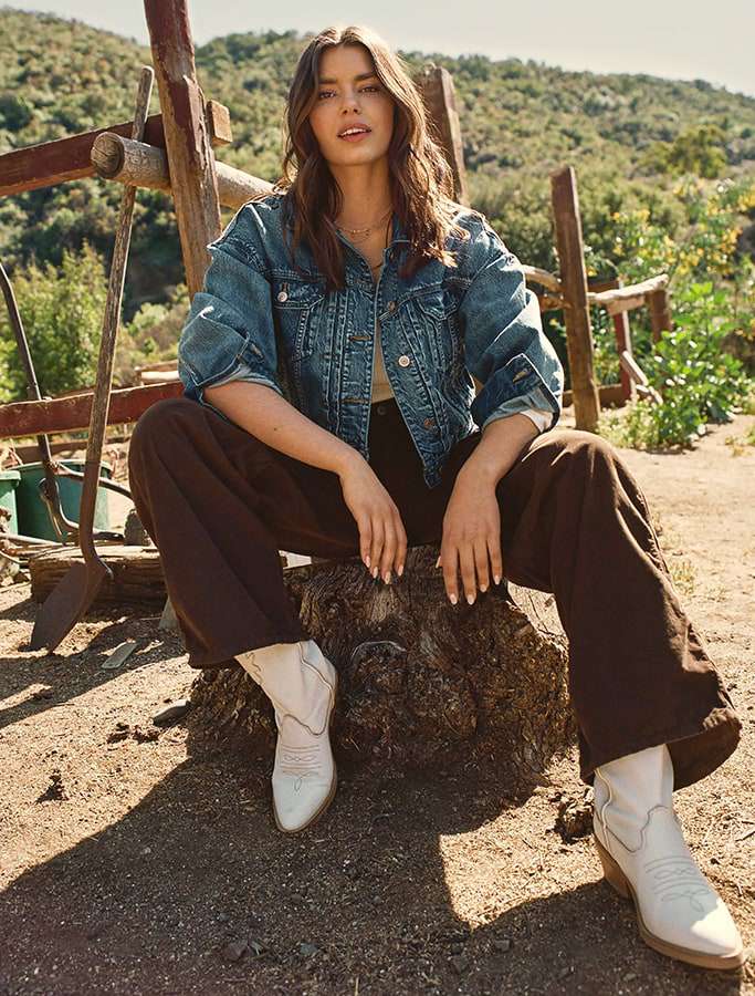 model in denim outerwear and brown flare pants with white cowgirl boots
