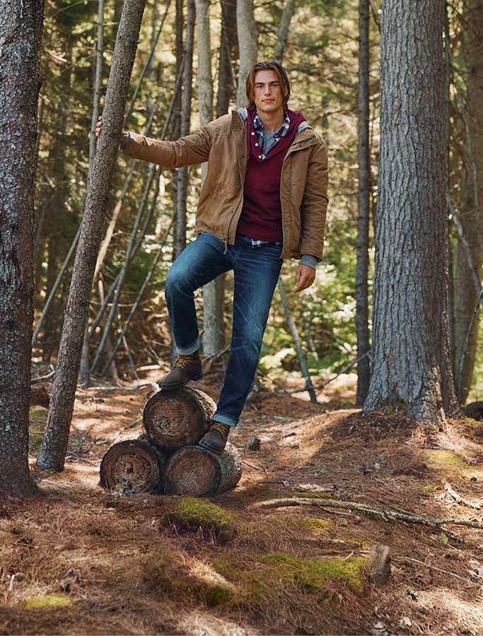 model in woods standing on logs