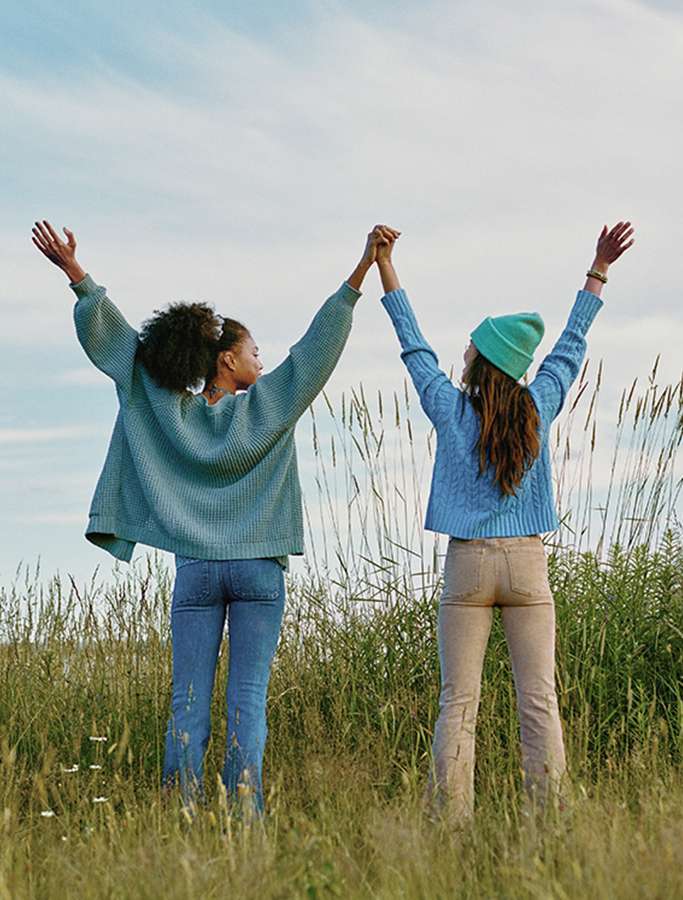 two models standing in field with arms up 