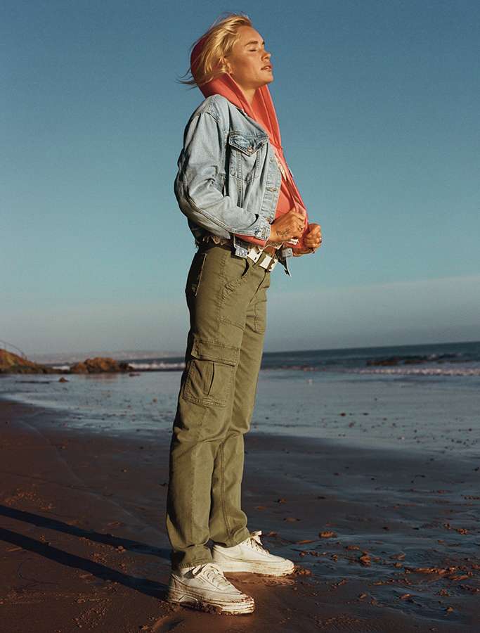 model on beach wearing green cargo pants and denim jacket