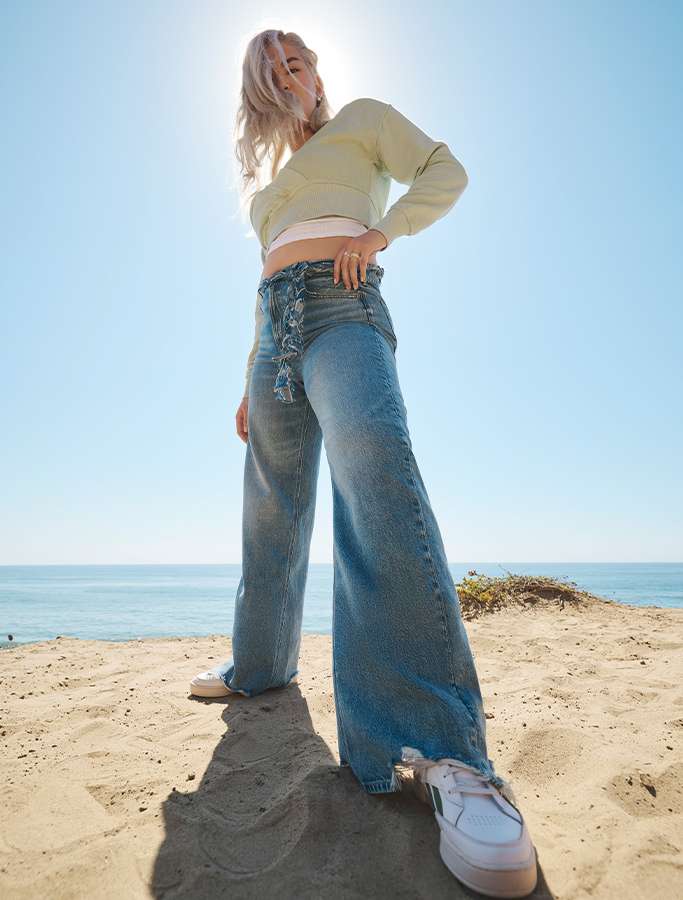 model on beach wearing AE wide leg jeans