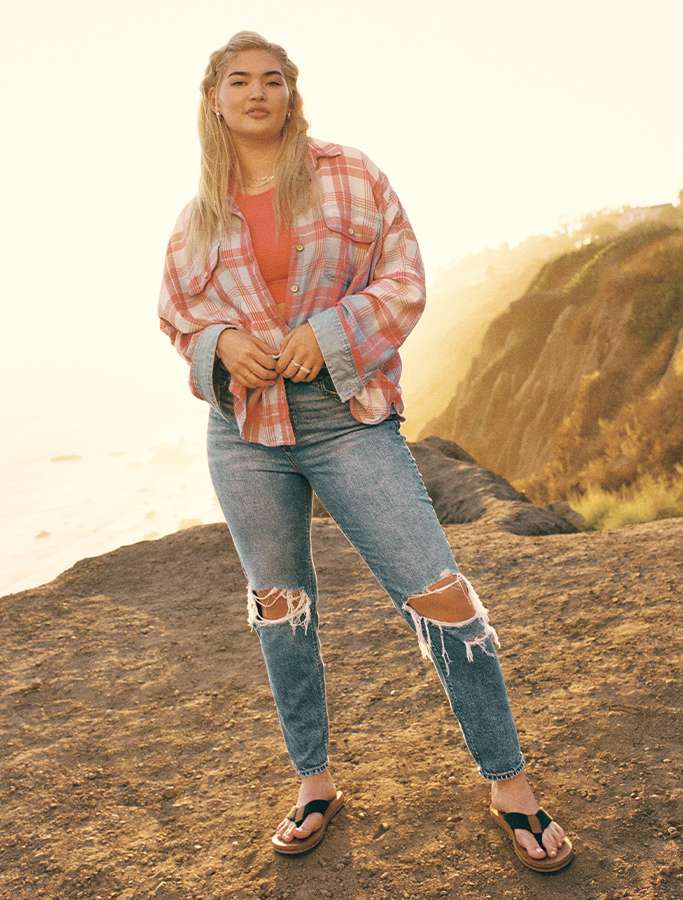 model wearing ripped jeans and flannel on the beach