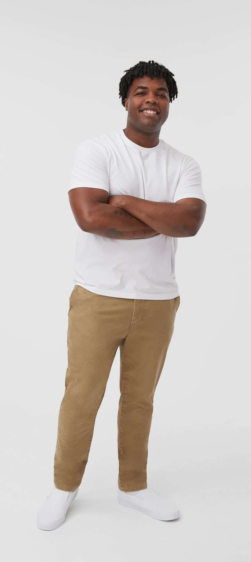 model wearing khaki pants and white t-shirt standing with arms crossed