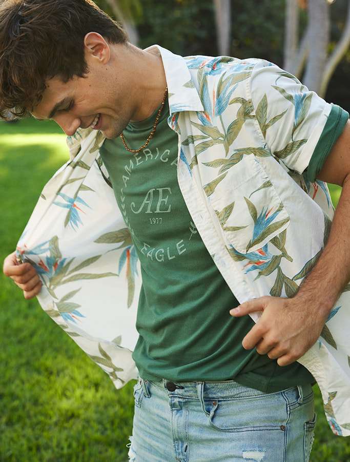 model in light blue denim jeans, a green graphic tee layered with a 
