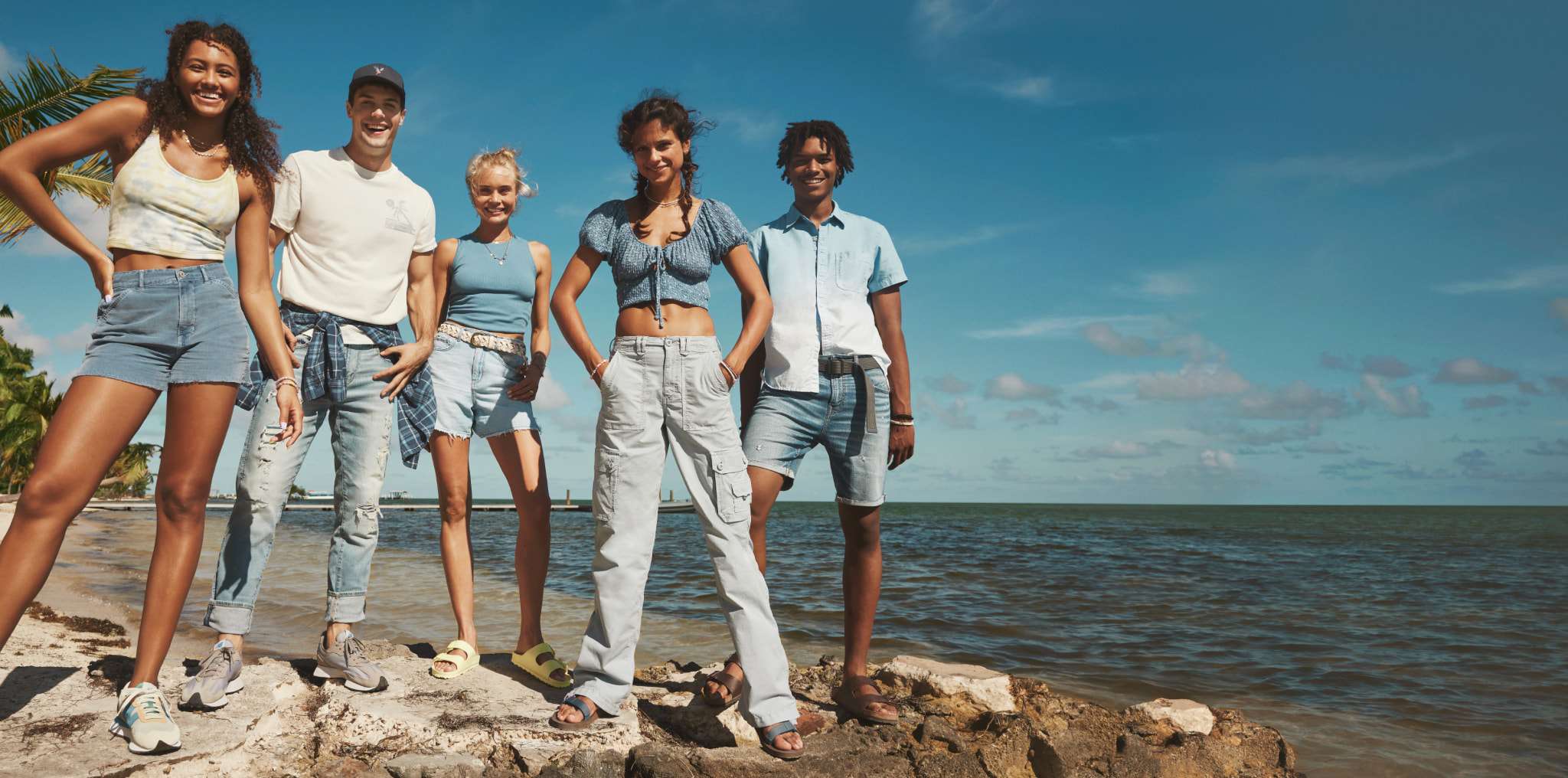 group of models on beach wearing AE jeans and shorts