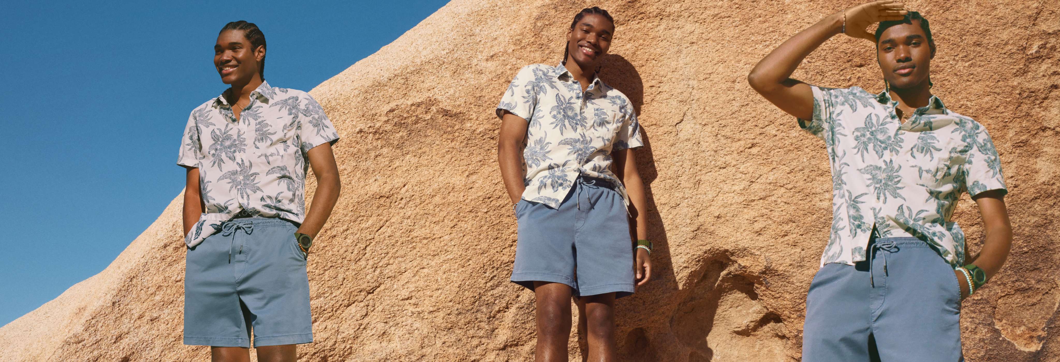 model standing on rocks wearing AE shorts and button down shirt