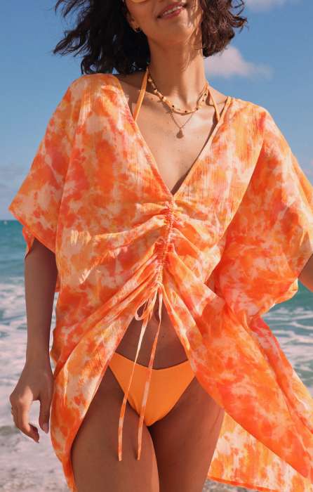 model in orange bikini and cover up on the beach
