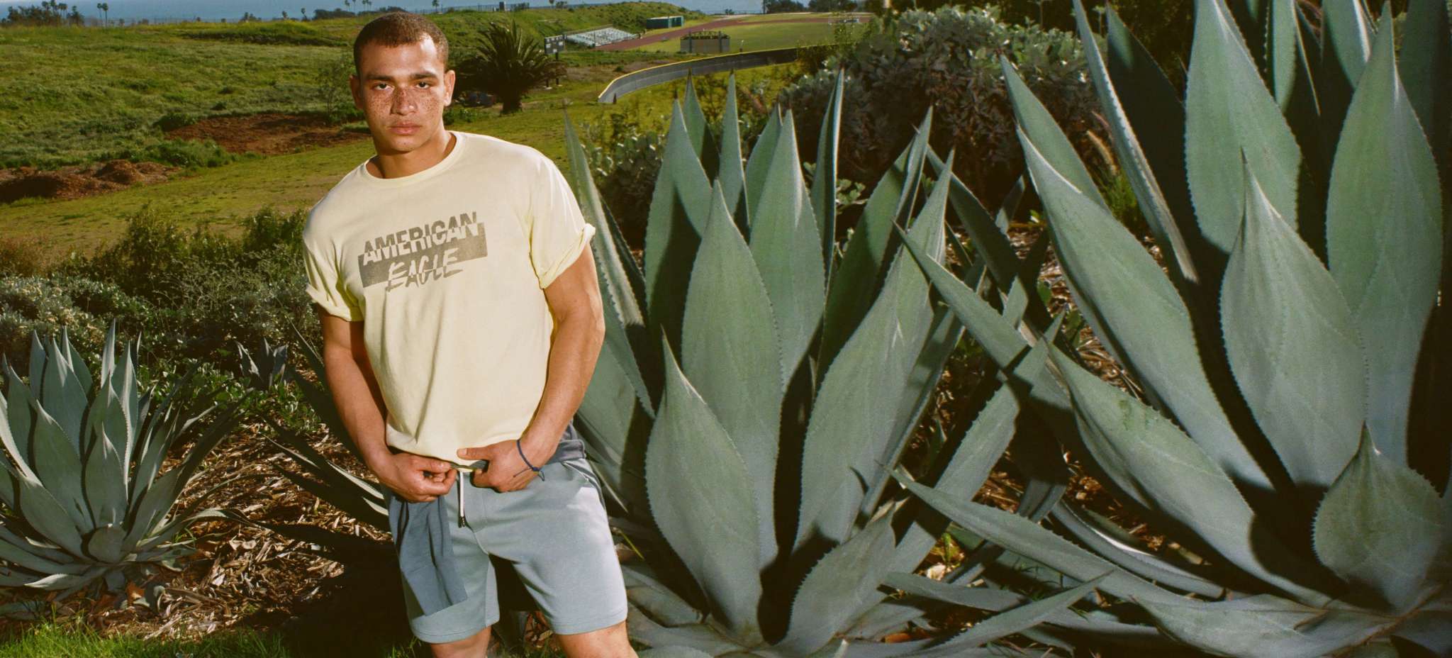 model standing in front of plants wearing AE shorts and t-shirt