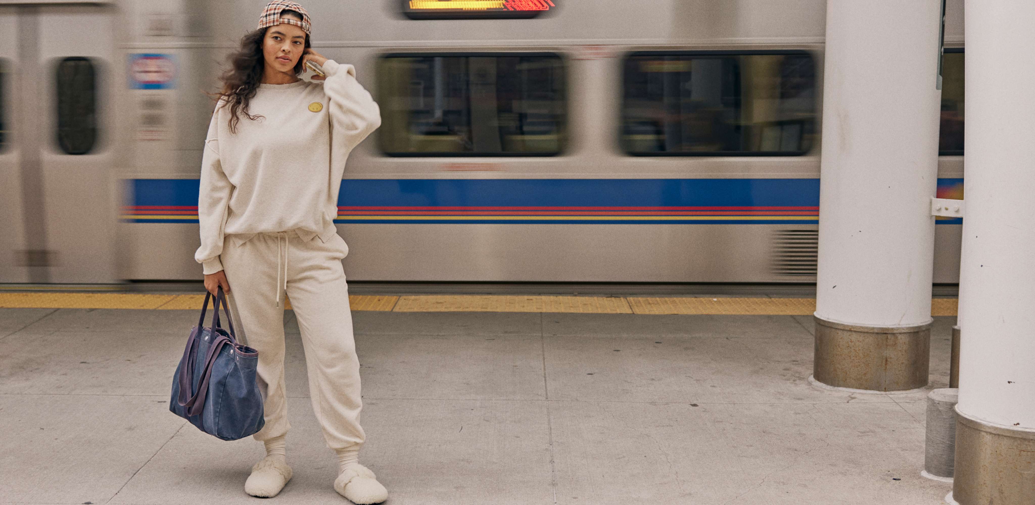 Model in front of subway wearing white crewneck and sweatpants 