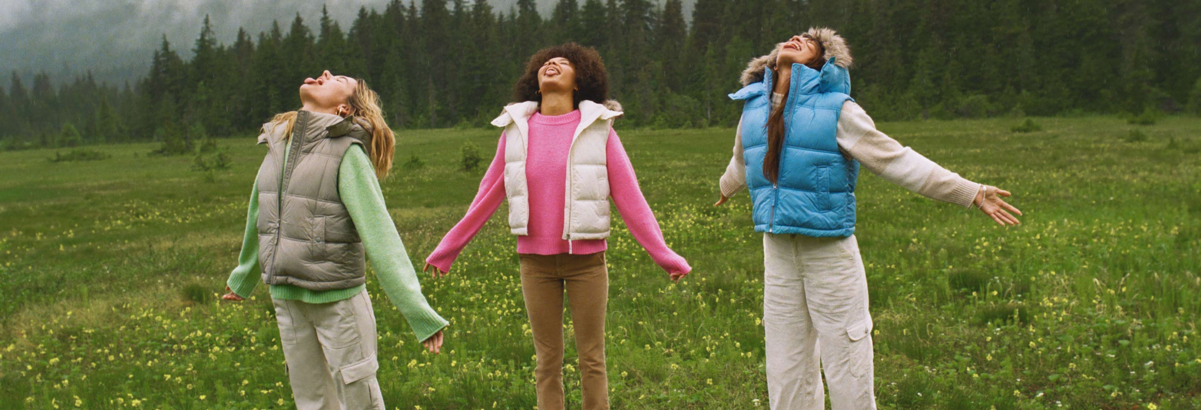 Three models wearing puffer vests and AE hoodies and pants