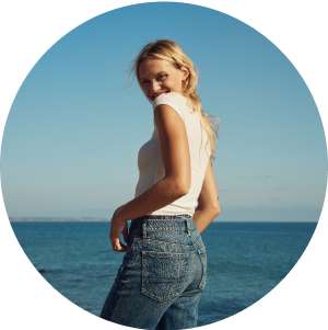 model in white top and jeans in front of ocea