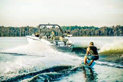 Woman Driving Heyday Wake Boat, Towing Rider, Port-Side Stern View