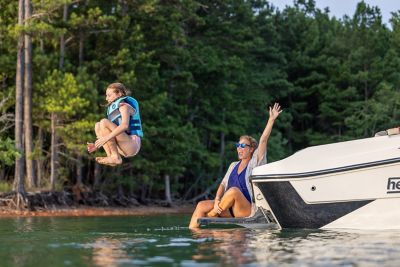 Girl jumping off of the back of an H22 wake boat