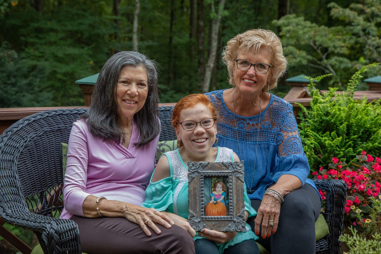 Friends sit on a bench smiling