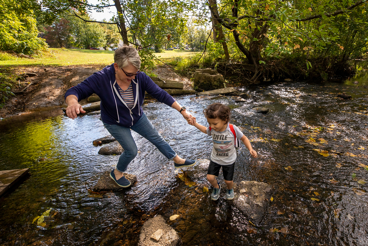a little boy and old woman explore a creek