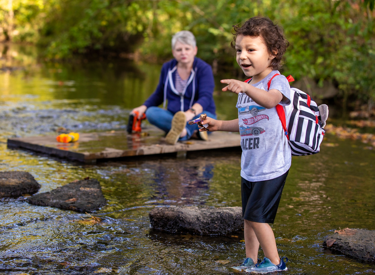 a little boy and old woman explore a creek