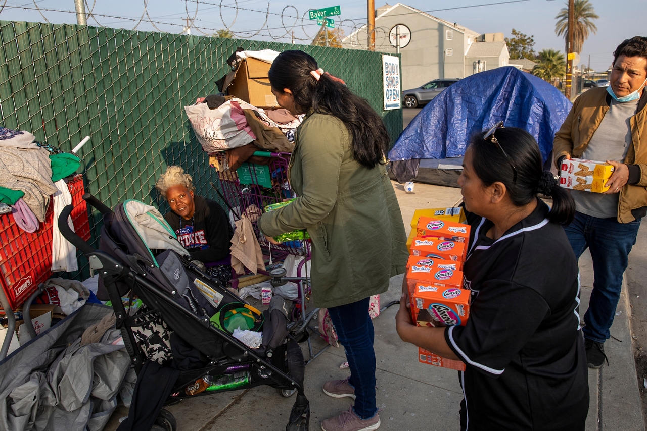 Rossana, Blanca and Jose offer a homeless woman cookies and invite her to the next day’s Boxes of Love® distribution and free lunch. Agape Church is visible in the background.