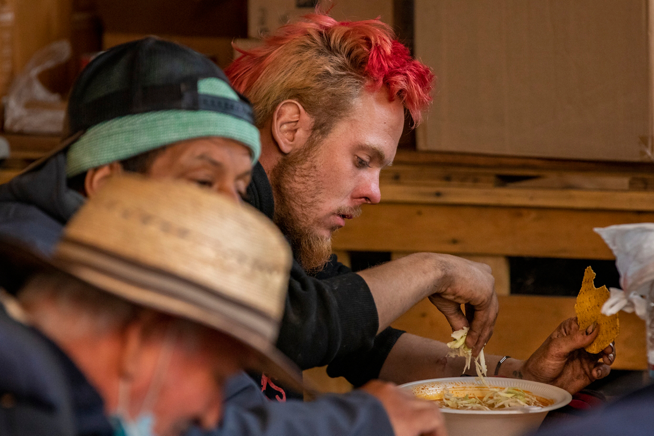 Homeless men from a nearby street mission eat a free lunch of hominy soup with shredded cabbage and tortillas during the Boxes of Love® distribution at Agape Church.