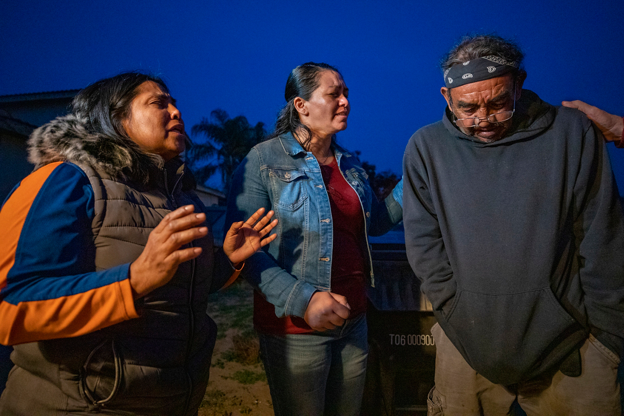 Blanca (left) and Rossana ask God to help 72-year-old farm worker Jose Luis fulfill his promise to his dying wife to take her ashes back to El Salvador for burial.