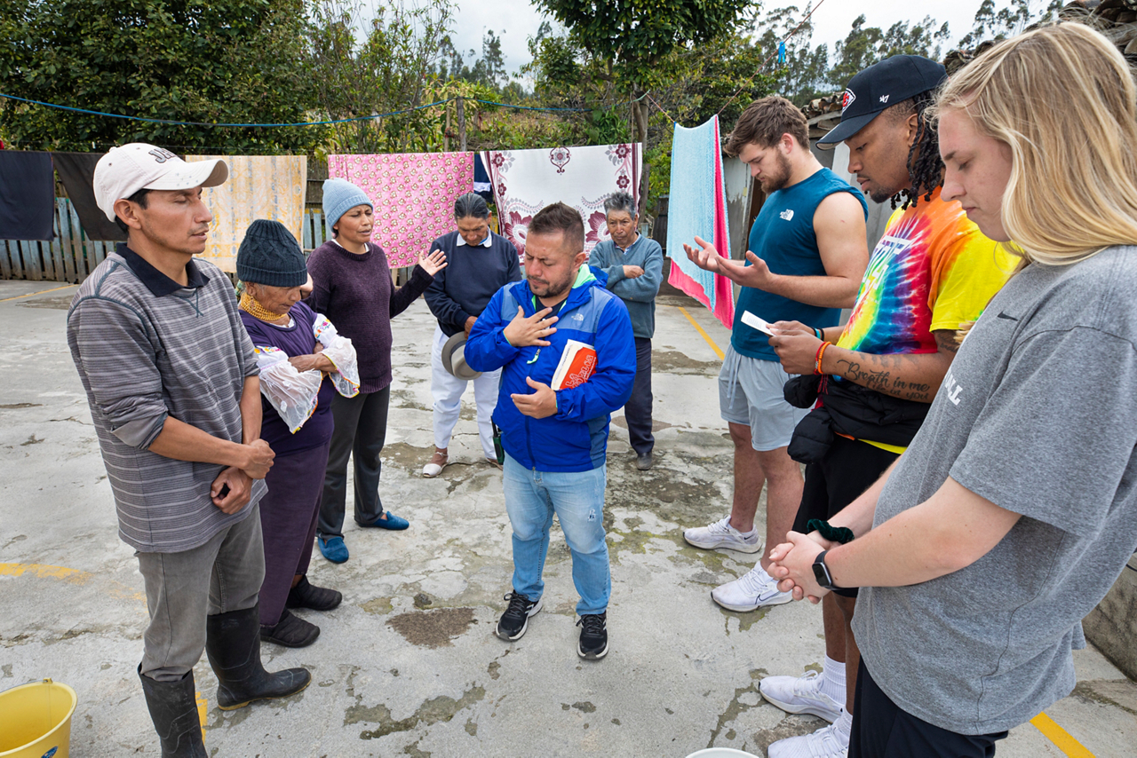Luis (left with hat) prays to invite Jesus into his life.