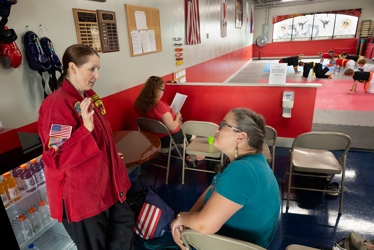 Melody talking with her son's karate teacher while she is taking a break. 
