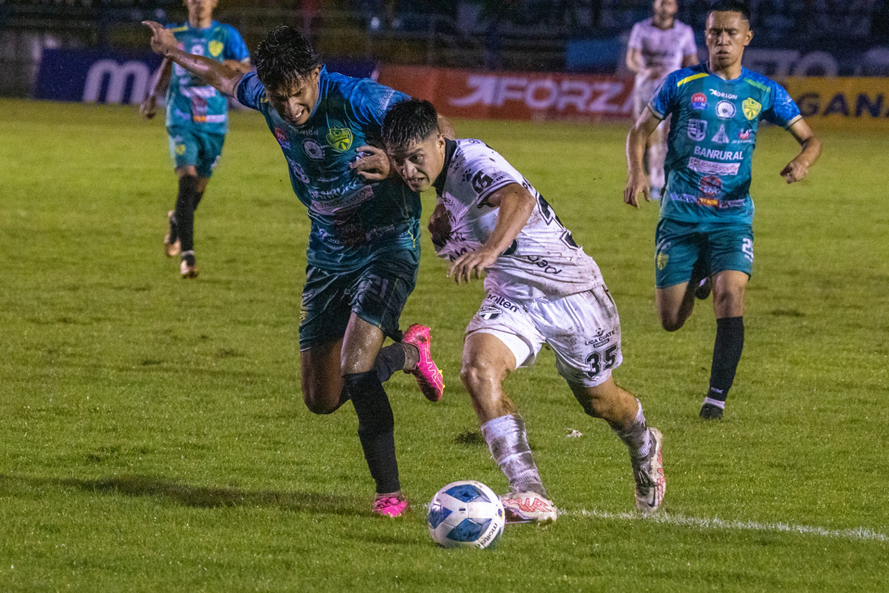 Xinabajul and Comunicaciones players battle for control of the ball.