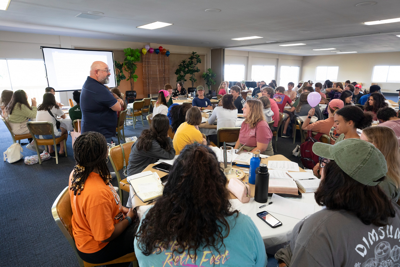 Brad Smith standing talking to a group of students around a table