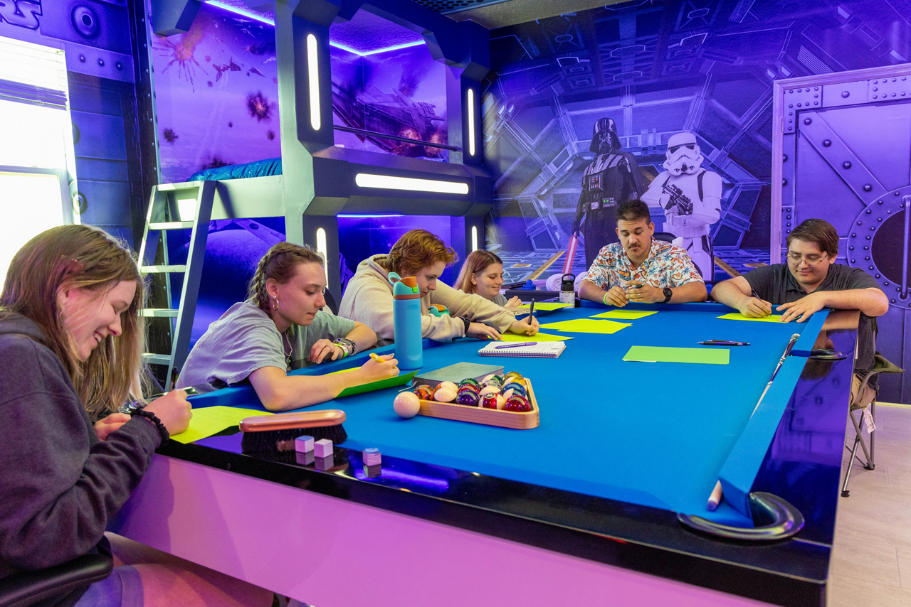 students work around a pool table in a Star Wars themed room
