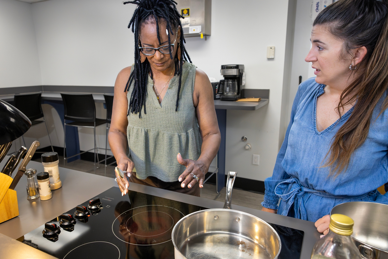 Lorna Johnson, losing sight article. Lorna is learning kitchen skills from Emily James, Lighthouse instructor. Hoe to pour water using a sensor to tell when the cup is full. How to fold her money to know the denominations, and using a reader to iniatially tell her the amounts. Learning to feel the heat of a burner, putting spices in her hand to measure the amount, and putting water into a pan to learn how to carry the pan and place it into the oven withour tilting the pan and spilling the water. 