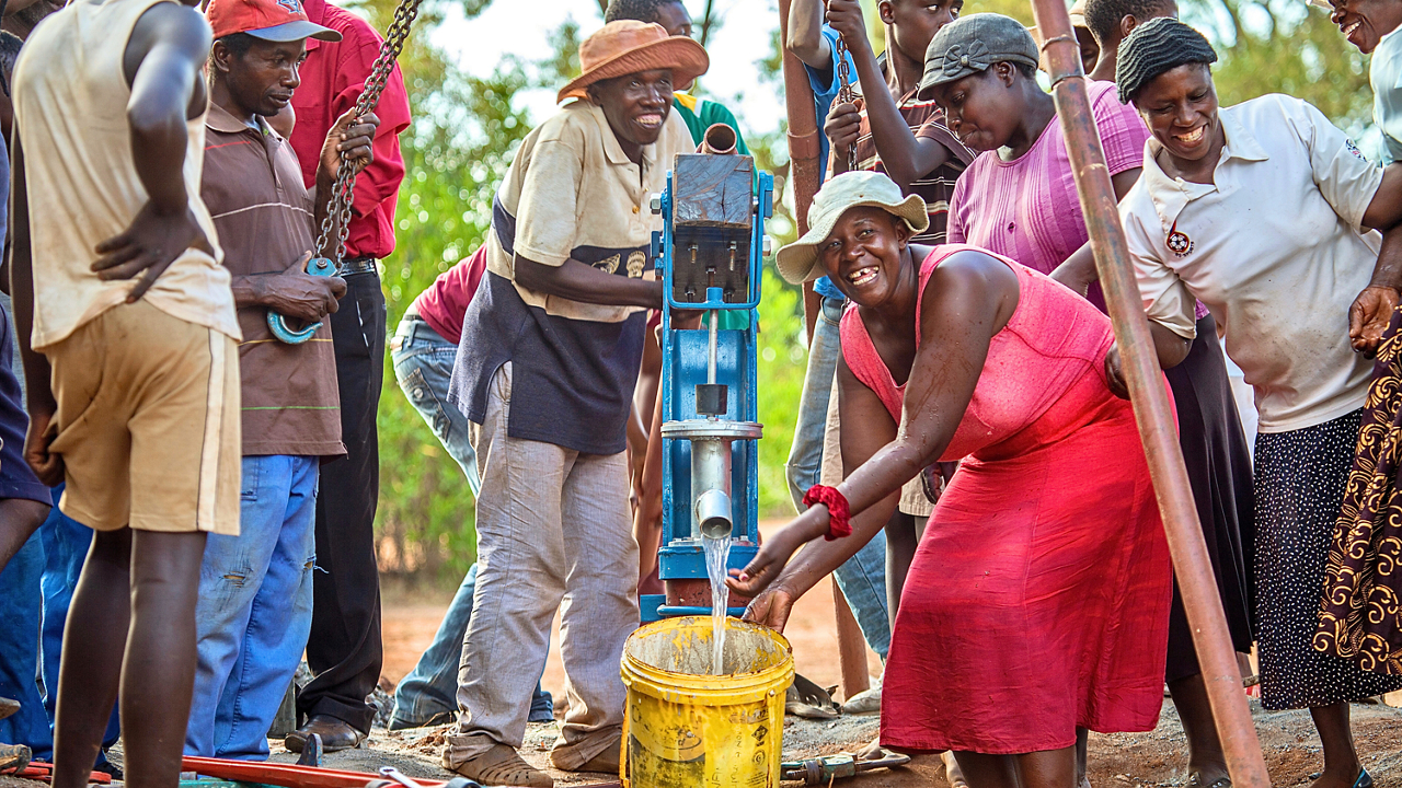 People expressing joy while pumping clean water