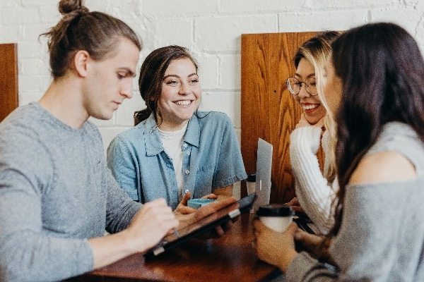 Students talking around a table and smiling.