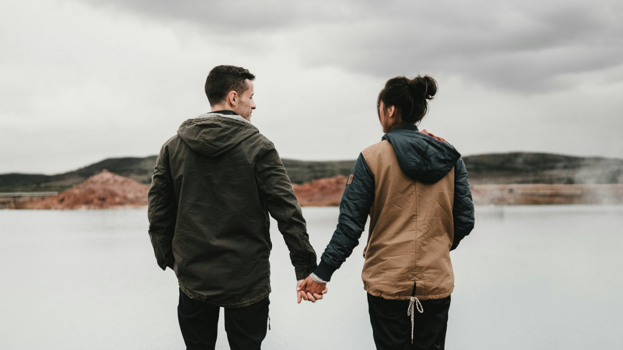 couple holding hands overlooking lake